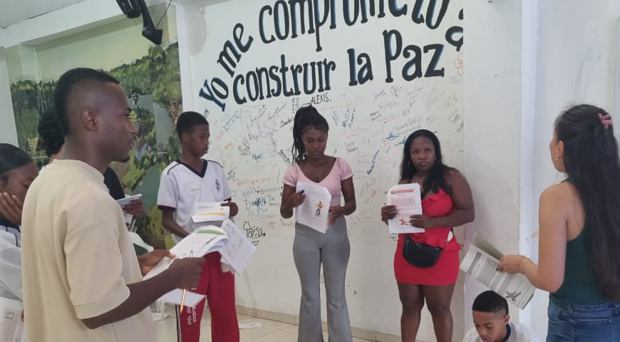 Docentes de Tumaco en un taller de Resiliencia y Compasión. Participan siete personas ubicadas de pie formando un círculo y siendo guiados por una maestra.