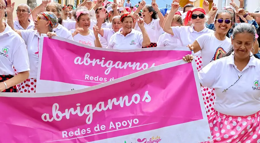 Mujeres del programa Abrigo, en Boyacá, desfilan con pancartas que dicen 'abrigamos' redes de apoyo